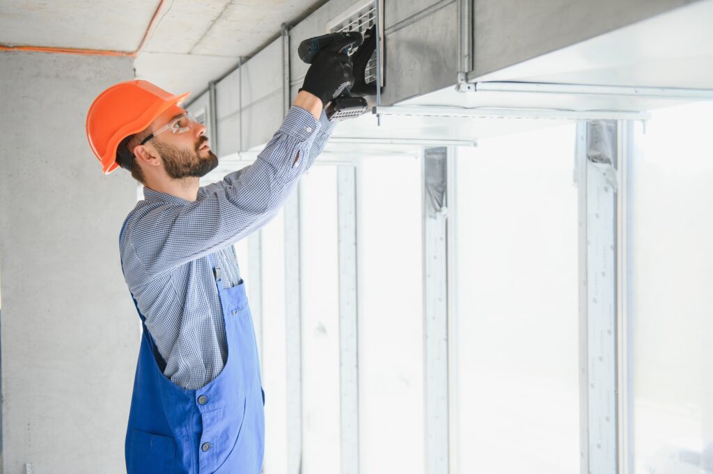 Warehouse Heating and Cooling System Installation by Professional Caucasian Technician.